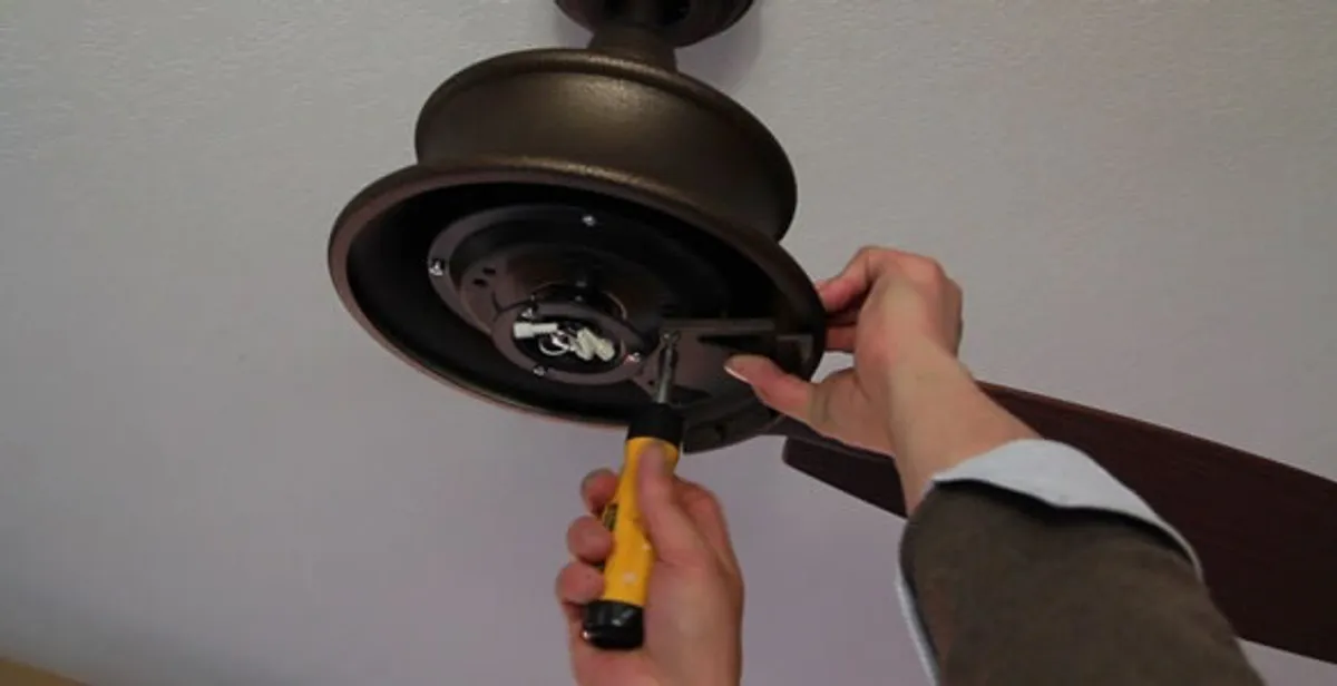 Electrician installing ceiling fan mounting bracket and fixture in Boston, MA