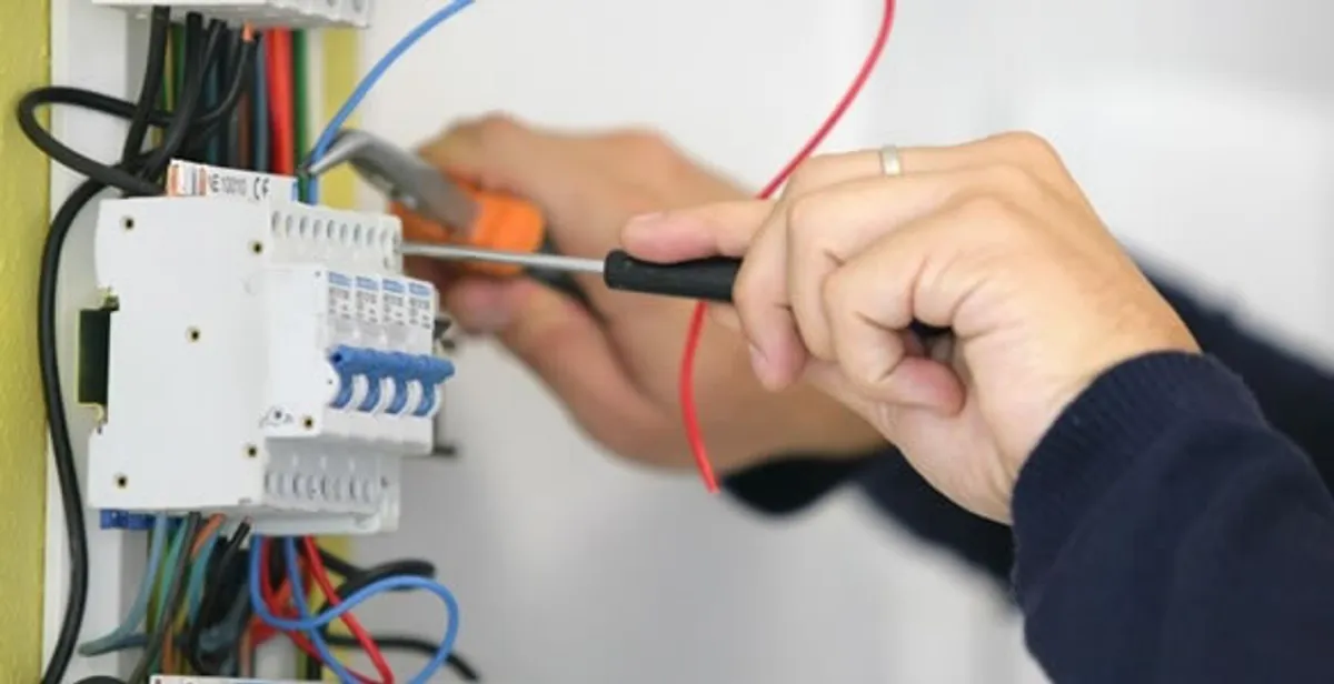 Electrician installing and adjusting circuit breakers in an electrical panel in Boston, MA