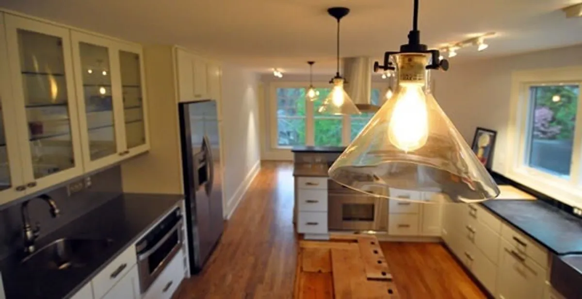 Residential electrician installing modern indoor light fixture in a home in Boston, MA