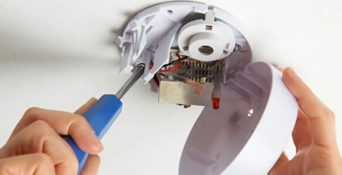 Certified technician wiring smoke detector during installation in Boston, MA